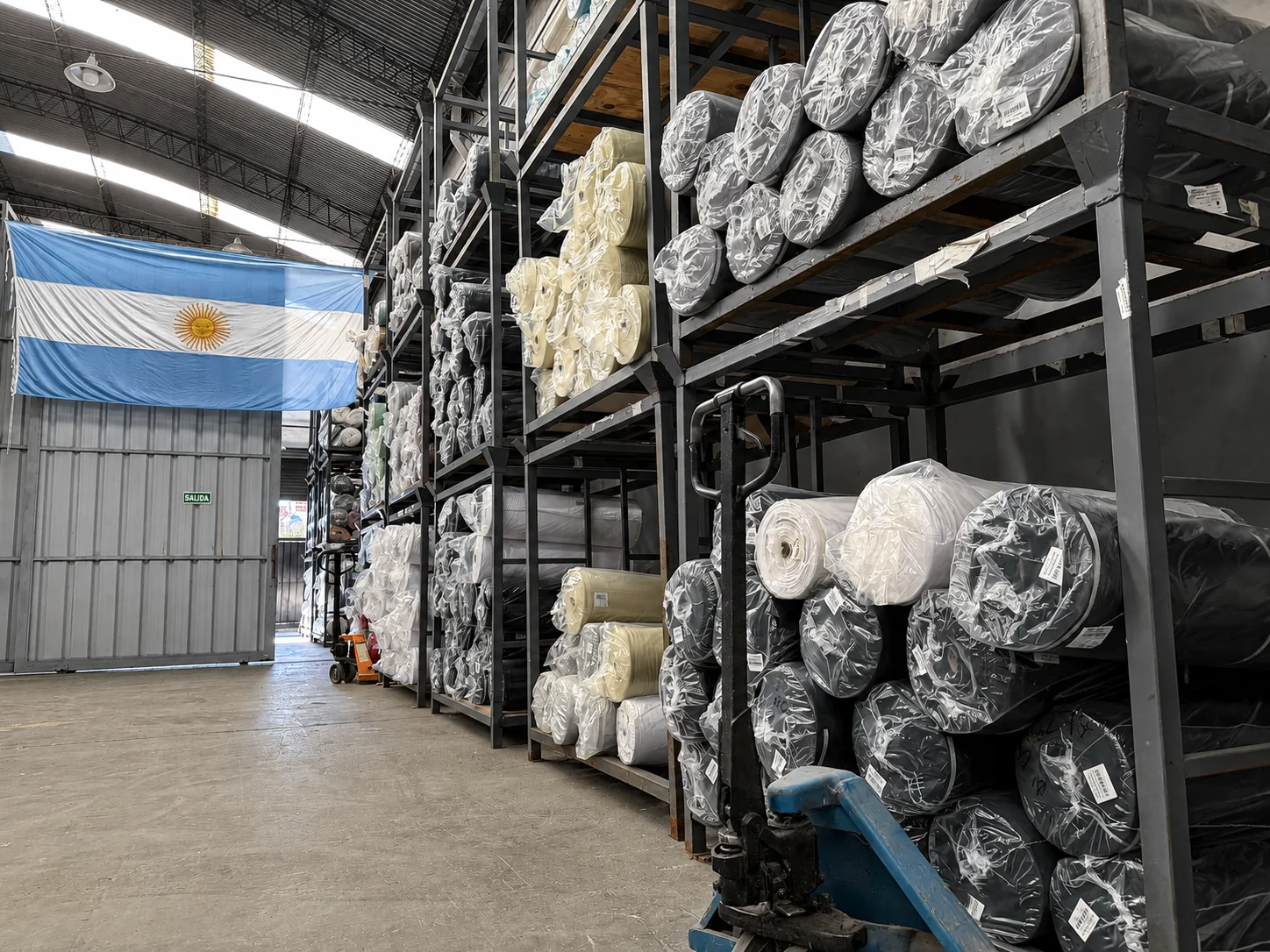 Depósito textil de JJTEX con rollos almacenados y la bandera argentina